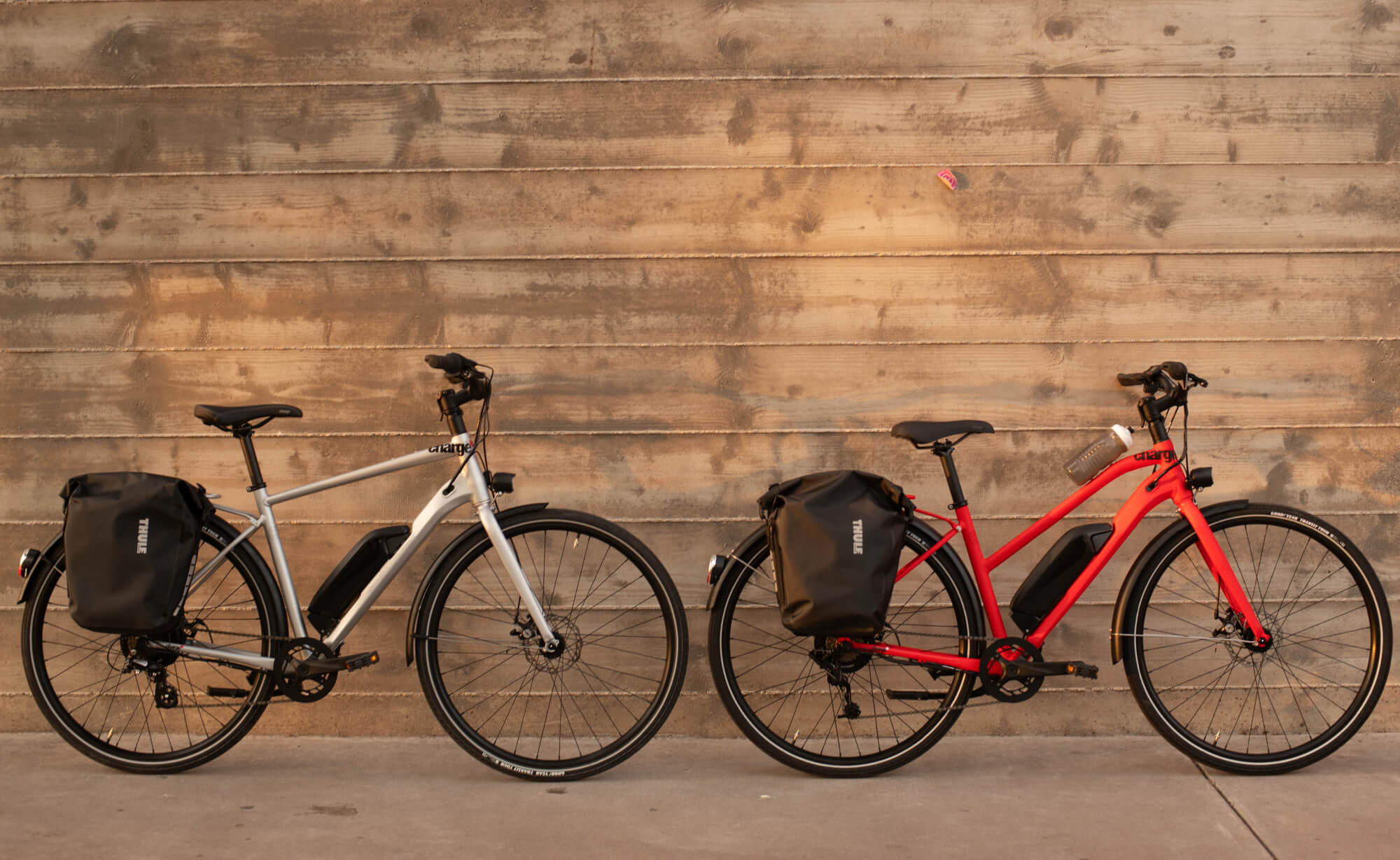 two charge electric bikes against a wooden wall